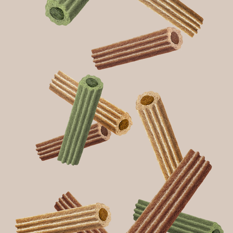 Assorted colors of crunchy dog treats shaped like hollow tubes are scattered on a light beige background.